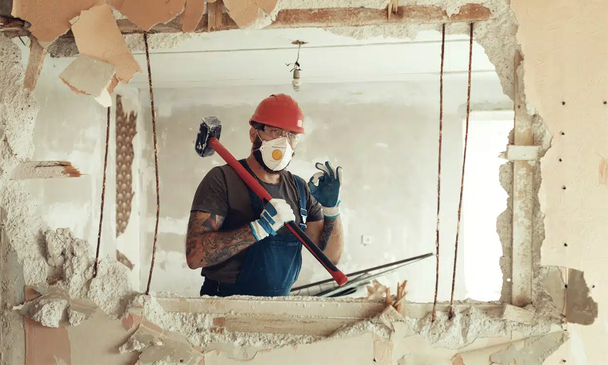 Artisan en train de faire de la démolition sur un chantier de rénovation de maison